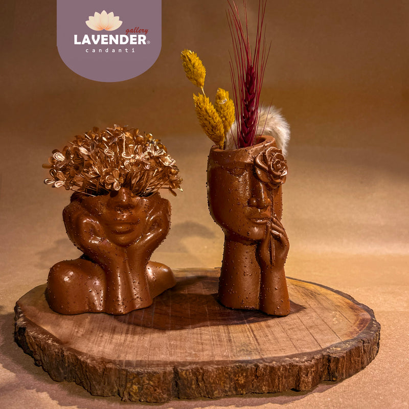 Two ceramic face vases with dried flowers 