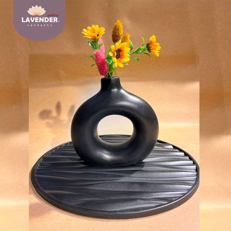 Black vase with flowers on a matching black tray 