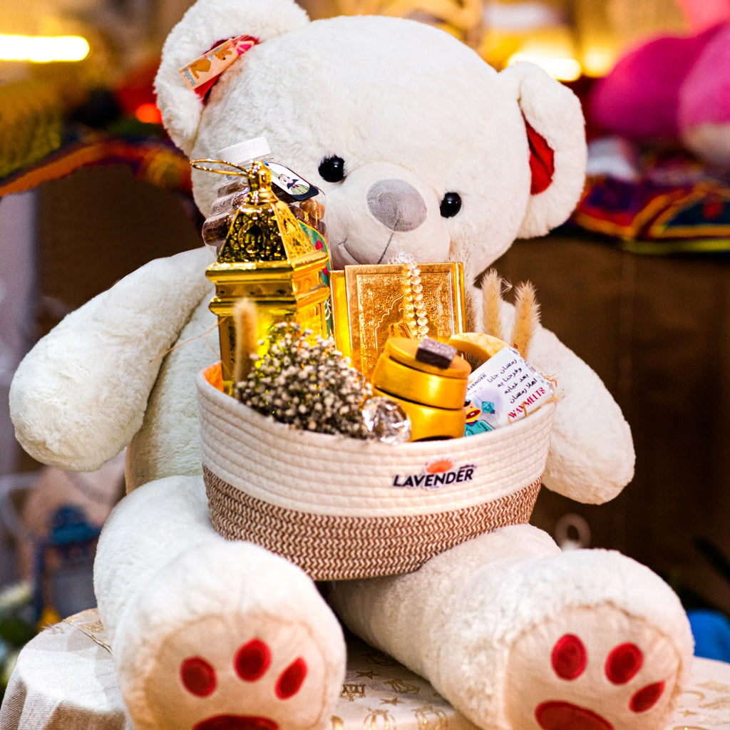 White teddy bear with a basket of gifts on a blurred background