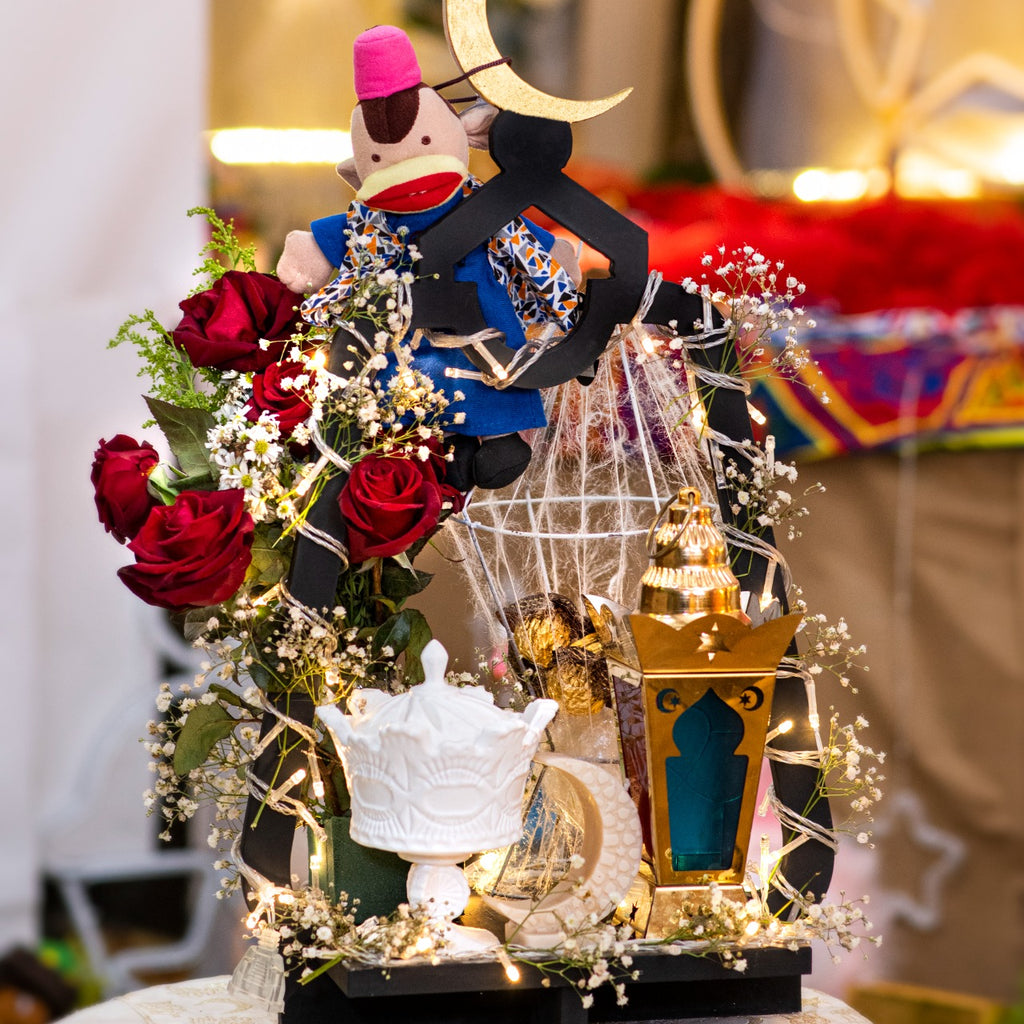 Decorative scene with a monkey figurine, flowers, and a lantern on a table.
