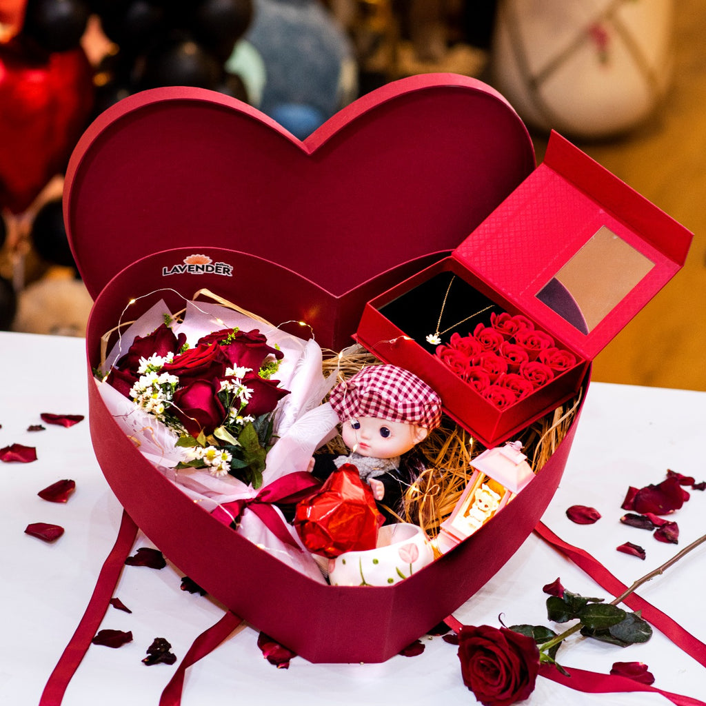 Heart-shaped gift box with a doll and flowers on a white surface
