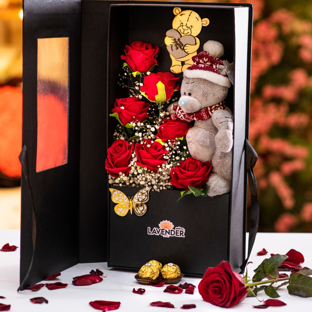 Gift box with teddy bear, roses, and chocolates on a decorative background