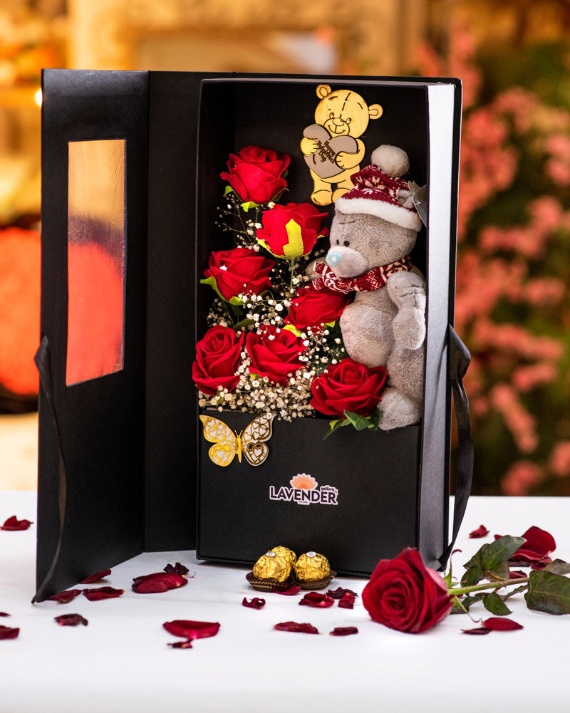 Gift box with teddy bear, roses, and chocolates on a decorative background