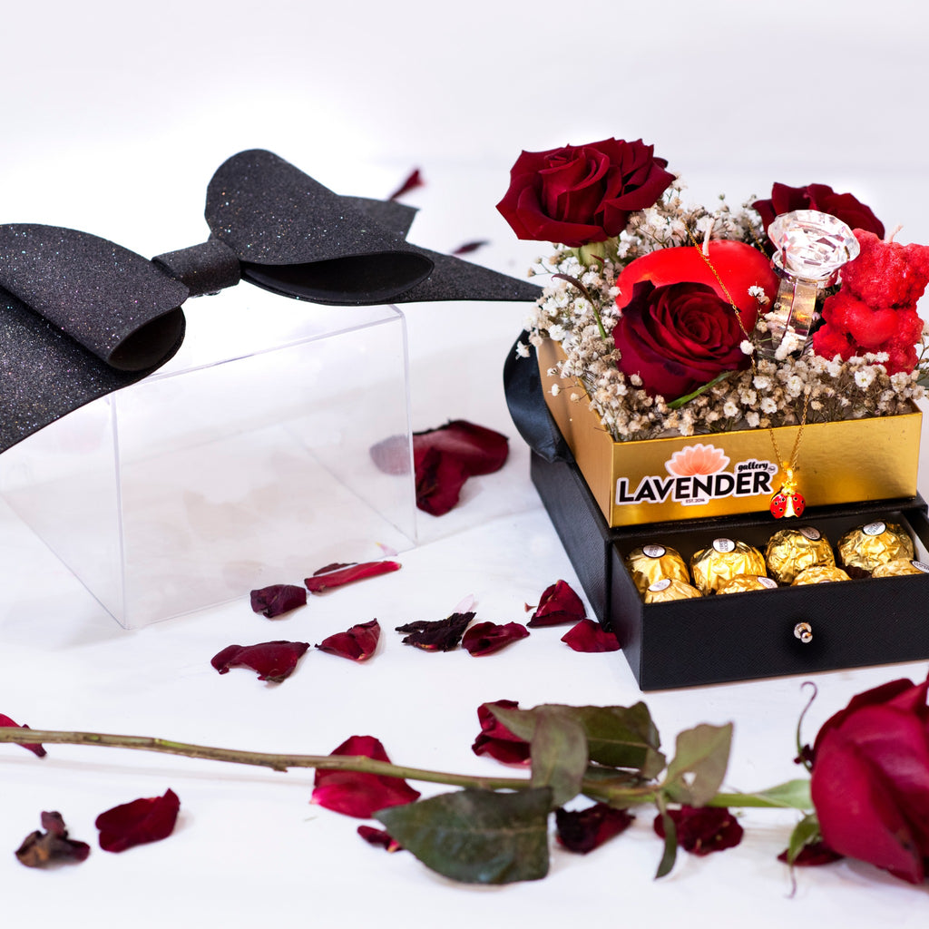 Decorative box with red roses and gold chocolates on a white background