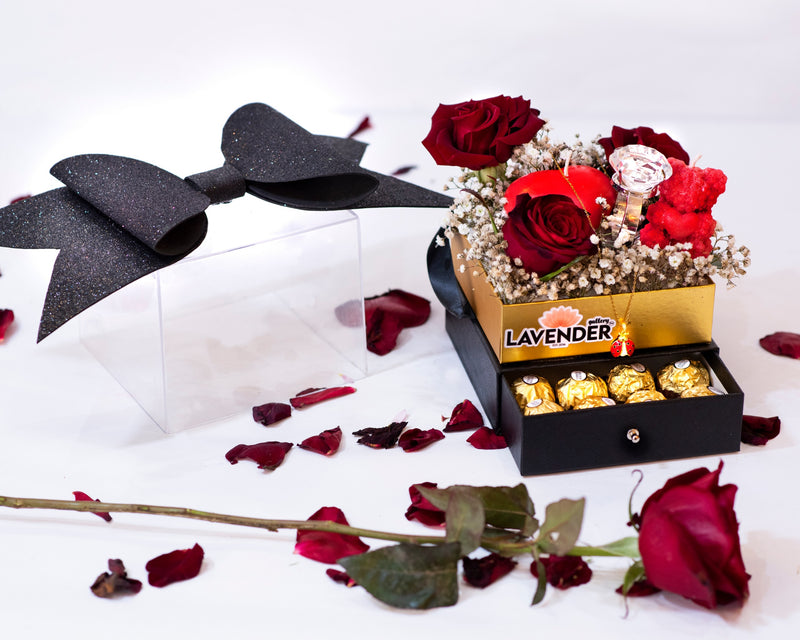 Decorative box with red roses and gold chocolates on a white background