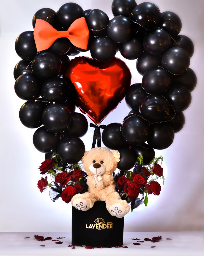 Heart-shaped balloon arrangement with a teddy bear and red roses, featuring the brand 'LAVENDER'.